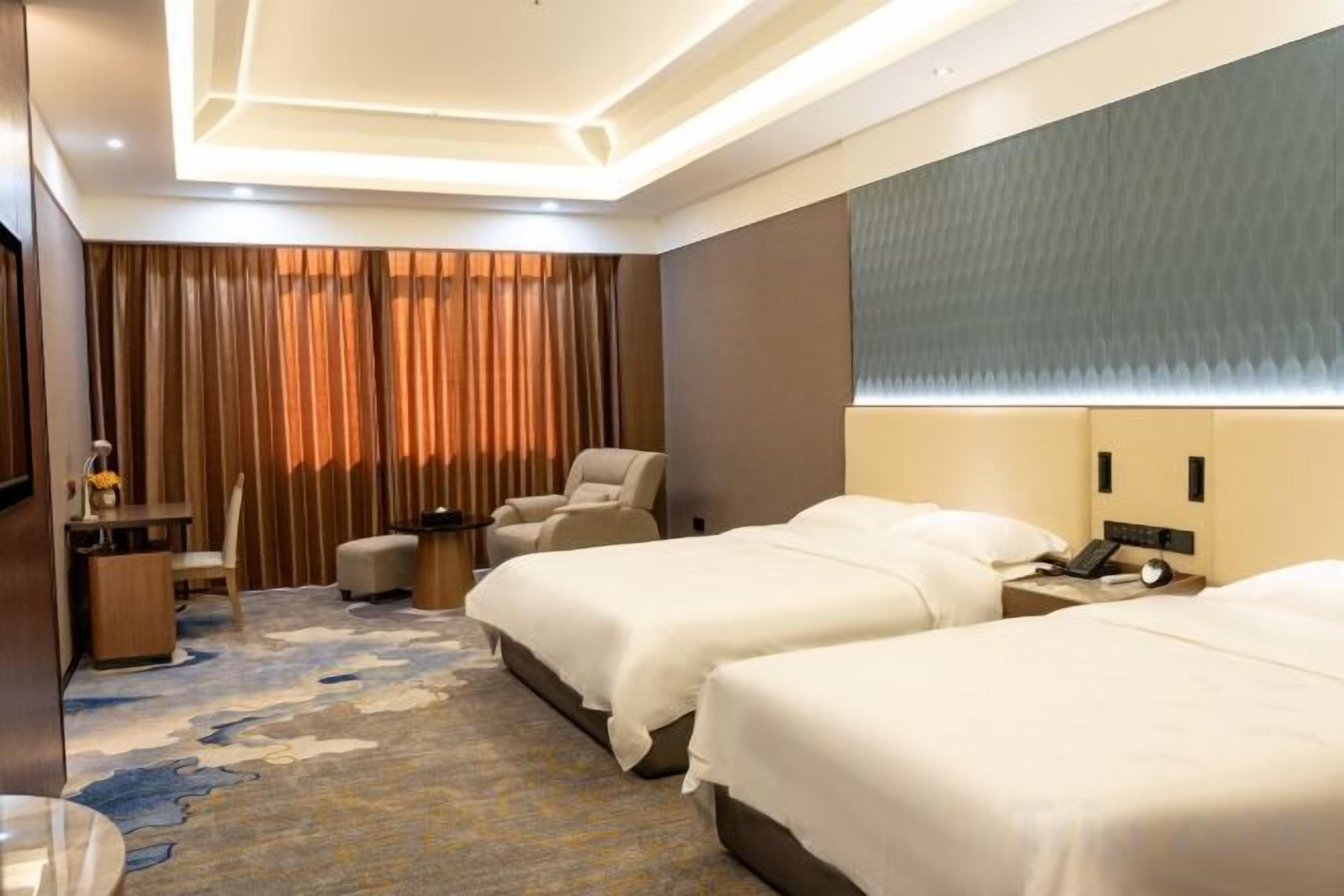 A hotel room with two beds, a desk, a chair, and a large window with curtains.