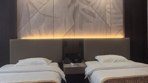 A hotel room with two beds, a nightstand, and a wall panel with leaf patterns. - GreenTree GEM International Hotel (Zaozhuang Station Municipal Government) (Zaozhuang)