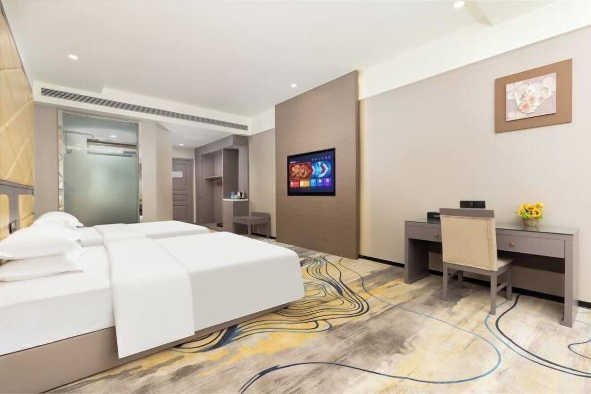 Een moderne hotelkamer met een bed, bureau, stoel en een wandgemonteerde flatscreen-tv.