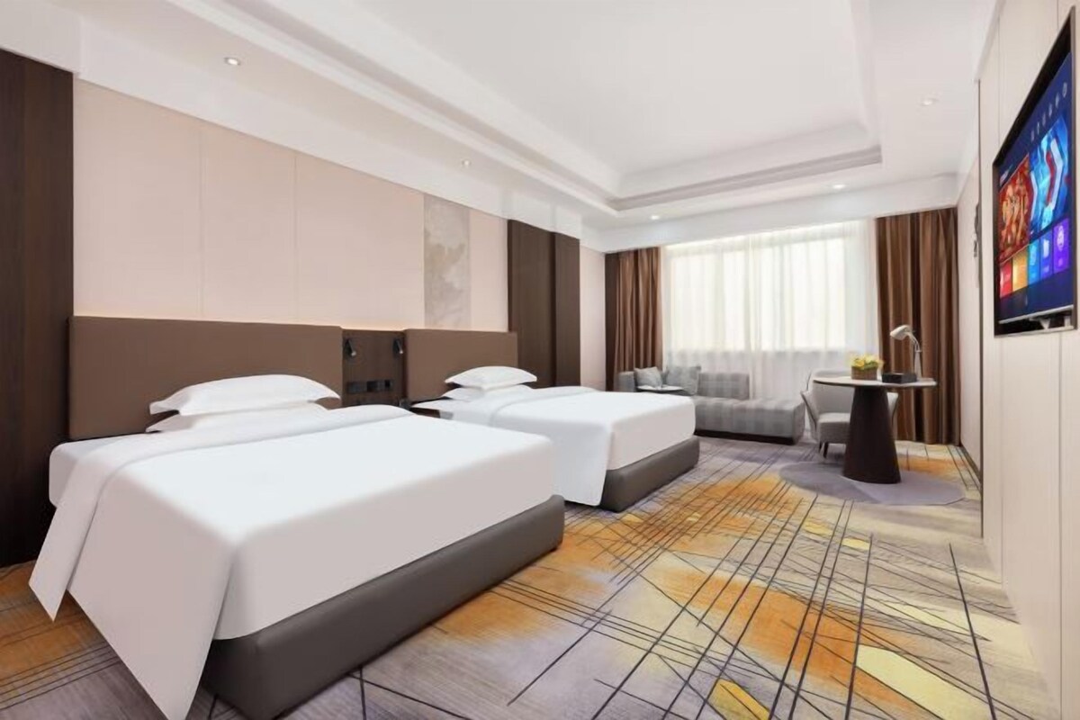 Een hotelkamer met twee bedden, een bank, een televisie en een bureau.