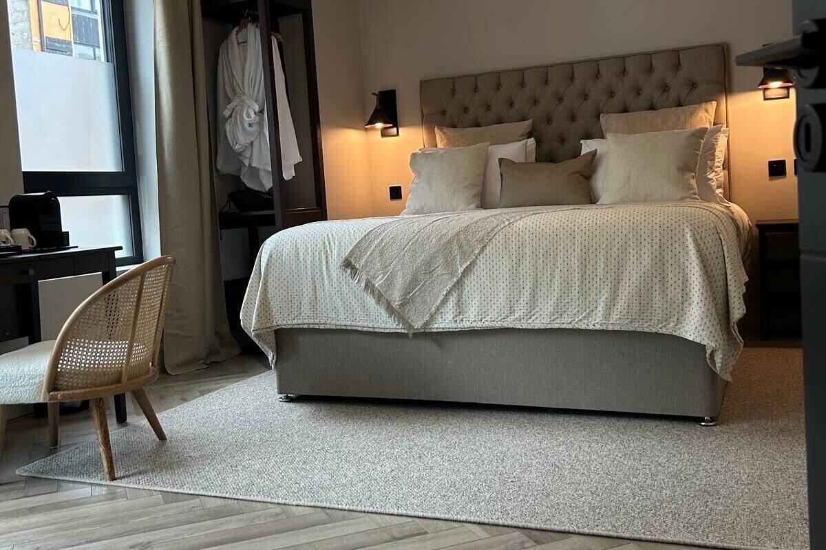 A modern hotel room with a large bed, a desk, and a chair.
