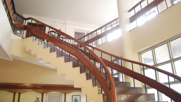 A multi-level interior with a curved wooden staircase connecting floors. - Grey Pelican Tourist Resort (Yamunanagar)
