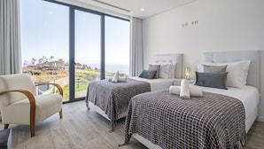 Une chambre d’hôtel moderne avec deux lits, une vue sur la mer et une grande fenêtre.