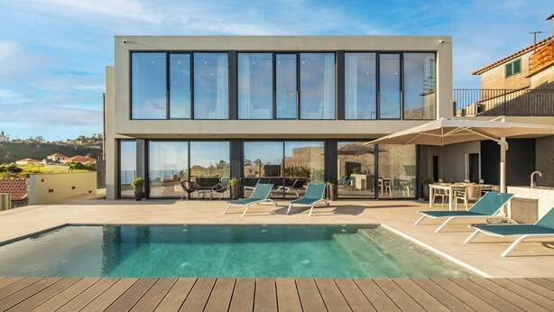 Une maison moderne dotée d’une piscine, de chaises longues et d’un espace patio.