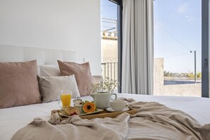 Un lit bien fait, avec un plateau de petit-déjeuner, des oreillers et une vue sur l’extérieur.