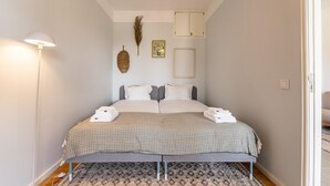 A neatly made bed with a patterned bedspread, a bedside lamp, and a decorative feather on the wall.