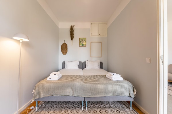 A neatly made bed with a patterned bedspread, a bedside lamp, and a decorative feather on the wall.