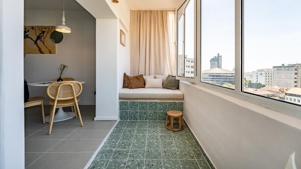 A modern apartment with a dining area, a small seating area by the window, and a view of the cityscape.