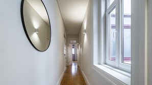 A hallway with a wooden floor, white walls, a large mirror, and a window. - Nomad s Family - 3bdr Charming Hideout Porto (Porto)