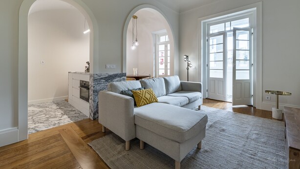 A modern living room with a sectional sofa, a small side table, and a marble-patterned rug. - Nomad s Family - 3bdr Charming Hideout Porto (Porto)