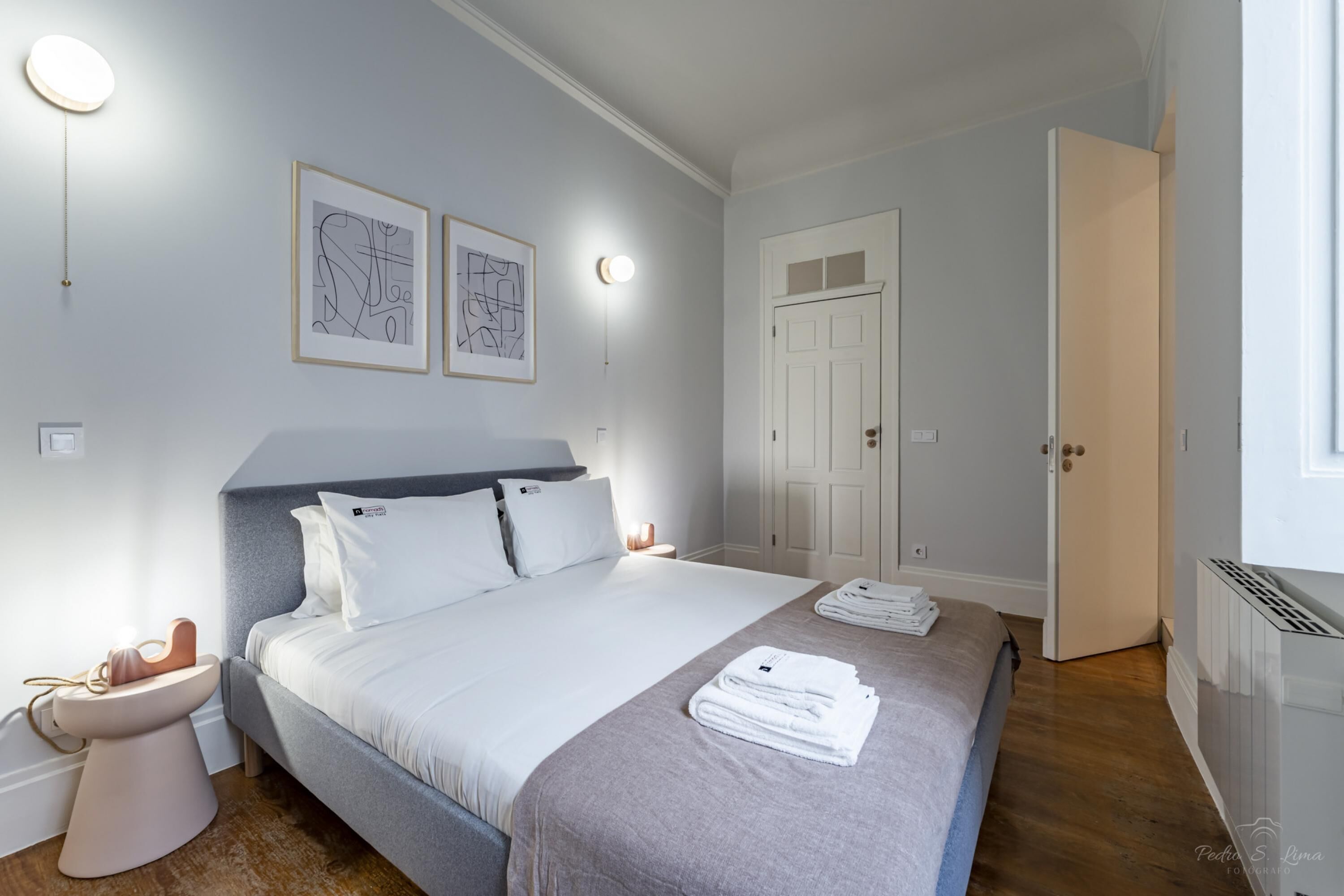 A modern bedroom with a large bed, bedside tables, a wardrobe, and artwork on the wall.