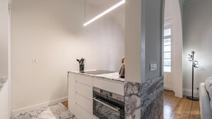 A modern kitchen with marble countertops, a built-in oven, and a pendant light. - Nomad s Family - 3bdr City Vibe Porto (Porto)