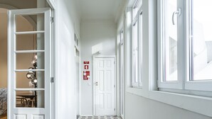 A hallway with a white door, a fire exit sign, and a patterned floor. - Nomad s Family - 3bdr City Vibe Porto (Porto)