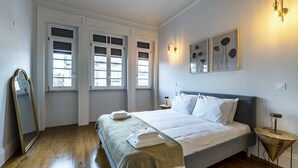 A bedroom with a bed, a bedside table, a mirror, and a window with shutters. - Nomad s Family - 3bdr City Vibe Porto (Porto)