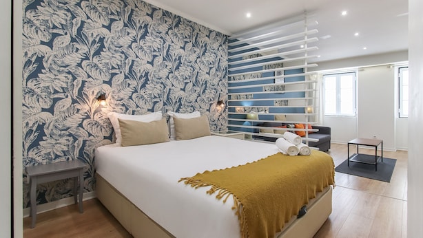 Un dormitorio moderno con una cama grande, una pared con diseño, una estantería empotrada y una mesita.