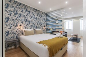 Une chambre moderne avec un grand lit, un mur décoré d’un motif, une étagère intégrée et une petite table.