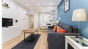 Una sala de estar moderna con un sofá, una mesa de centro, un televisor y una lámpara.