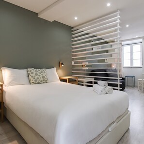 Una habitación de hotel moderna con una cama grande, televisión integrada, escritorio y ventana.