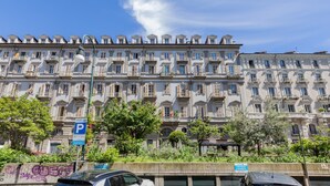 A row of multi-story buildings with balconies, a parking sign, and some greenery in front. - Casa a Porta Palazzo by Wonderful Italy (Turin)