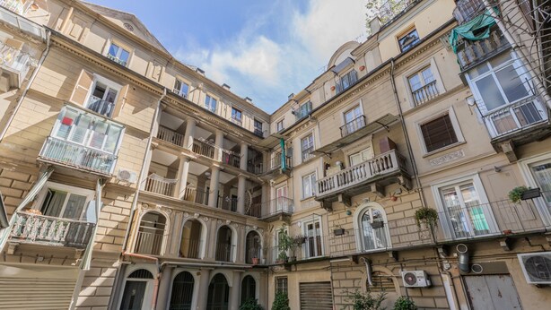 A multi-story building with balconies, arched doorways, and a courtyard. - Casa a Porta Palazzo by Wonderful Italy (Turin)
