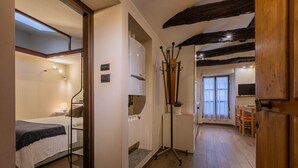 A hotel room with a bed, a desk, a chair, a coat rack, and a television. - Casa a Porta Palazzo by Wonderful Italy (Turin)
