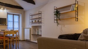 A living room with a sofa, a coffee table, a TV, and a dining area with chairs and a table. - Casa a Porta Palazzo by Wonderful Italy (Turin)