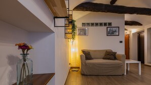 A cozy living room with a sofa, a small table, and a vase with flowers on a wooden shelf. - Casa a Porta Palazzo by Wonderful Italy (Turin)