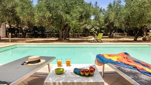 A poolside area with lounge chairs, a table with a hat, glasses, and a bowl, and a colorful towel. - Villa Giovanna con Piscina by Wonderful Italy (Castellammare del Golfo)