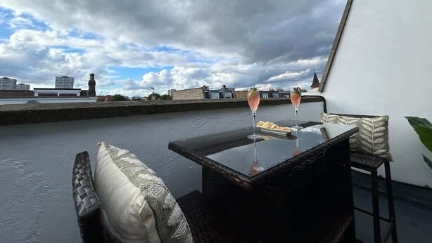 A rooftop terrace with a table, two chairs, and a glass of drink. - Battersea Park 7 Min walk • Balcony • Cafés Below (London)