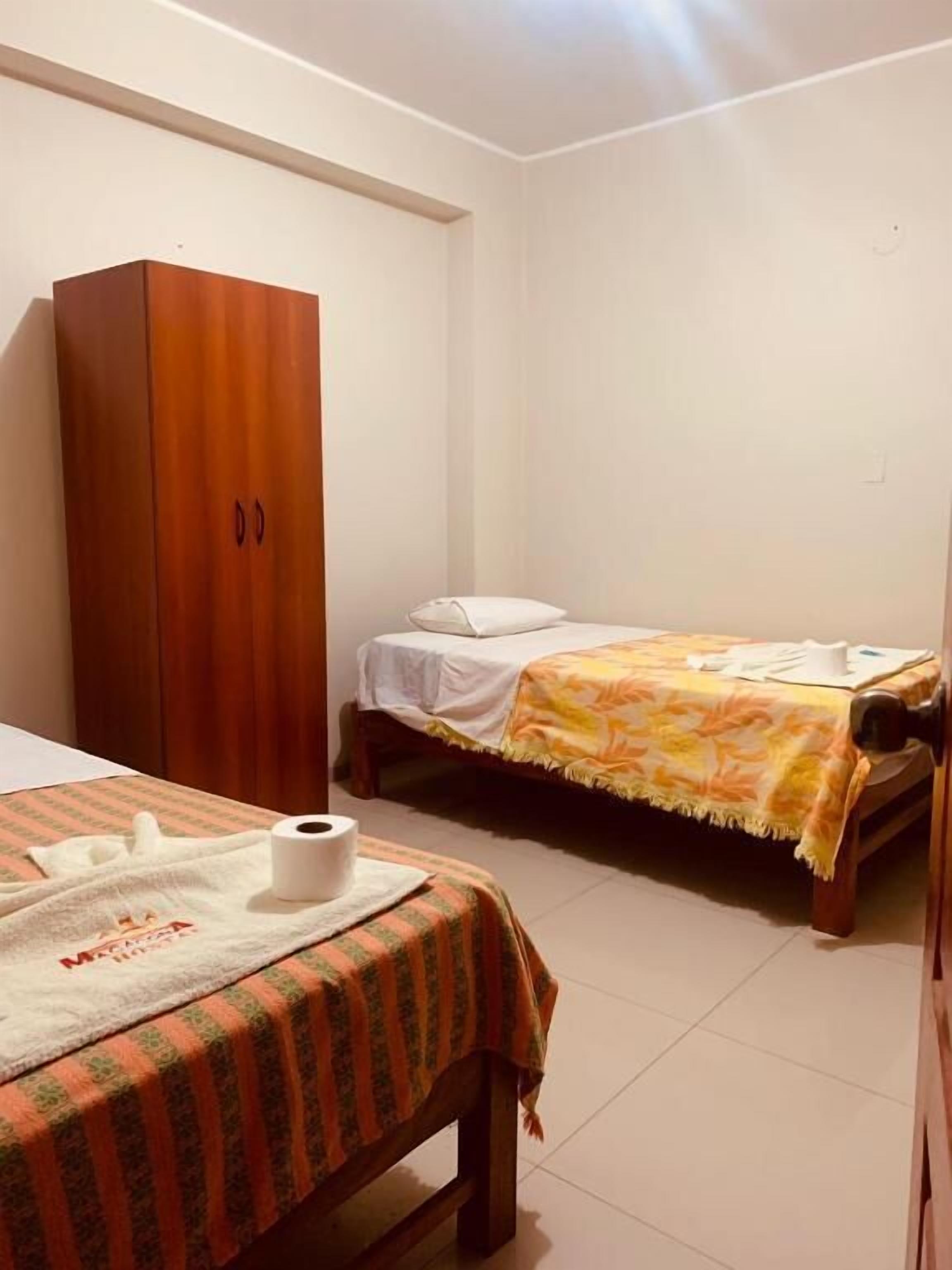 A bedroom with two beds, a wardrobe, and a bathroom.