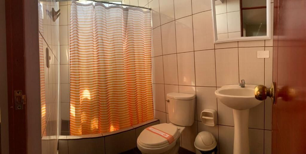 Un baño con cortina de ducha a rayas, un inodoro y un lavabo.