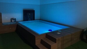 A modern bathroom with a wooden bathtub, a small sink, and a shower area. - Hostal Macacona  (Subtanjalla)
