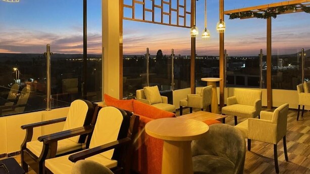 A rooftop lounge with large windows, modern furniture, and hanging lights. - Hostal Macacona  (Subtanjalla)
