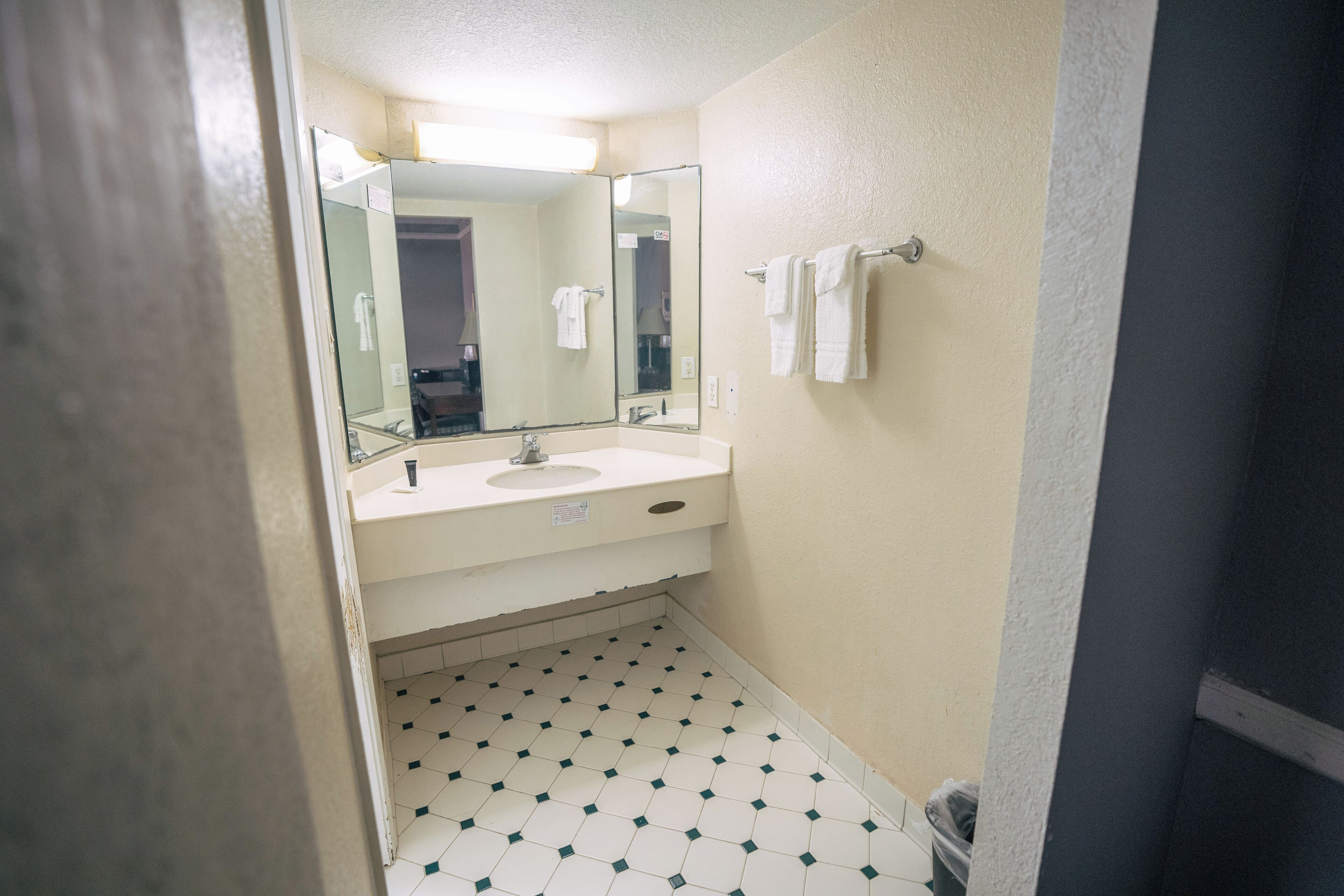 A small bathroom with a sink, mirror, and tiled floor.