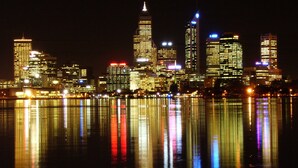A nighttime city skyline reflected in calm waters. - Guest Inn & Suites (Peachtree Corners)