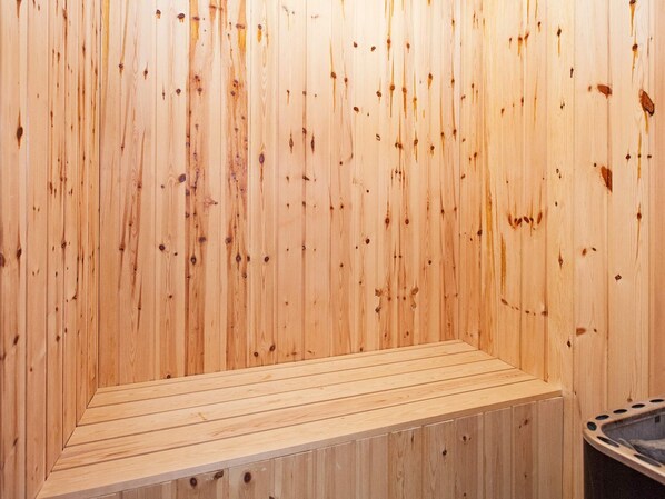 Un sauna avec des murs en bois et un banc.