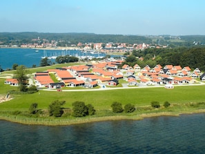 Un village côtier avec des maisons aux toits rouges, un port de plaisance et un lac.