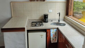 Eine kleine Küche mit Gaskochfeld, einer Kaffeemaschine und einem Spülbecken.