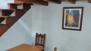 Ein Essbereich mit Holztisch und -stühlen, einer Treppe und einem gerahmten Gemälde an der Wand.