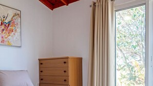 Un dormitorio con cama, cómoda de madera y ventana con cortinas.