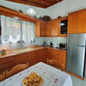 A kitchen with wooden cabinets, a stainless steel refrigerator, a sink, and a table with a floral tablecloth.