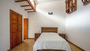 Ein Schlafzimmer mit einem hölzernen Bett, zwei Nachttischen, einem Schrank und einem Oberlicht.