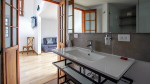 Ein modernes Badezimmer mit einem großen Waschbecken, Holzfenstern und einer sichtbaren Duschkabine.