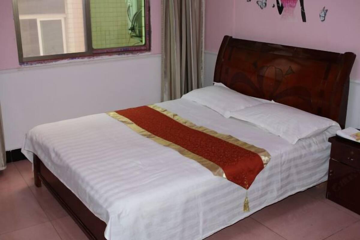 A single bed with a wooden headboard in a room with a window and a curtain.