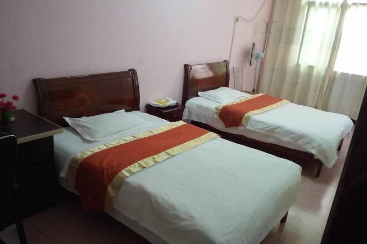 A hotel room with two beds, a desk, and a chair.