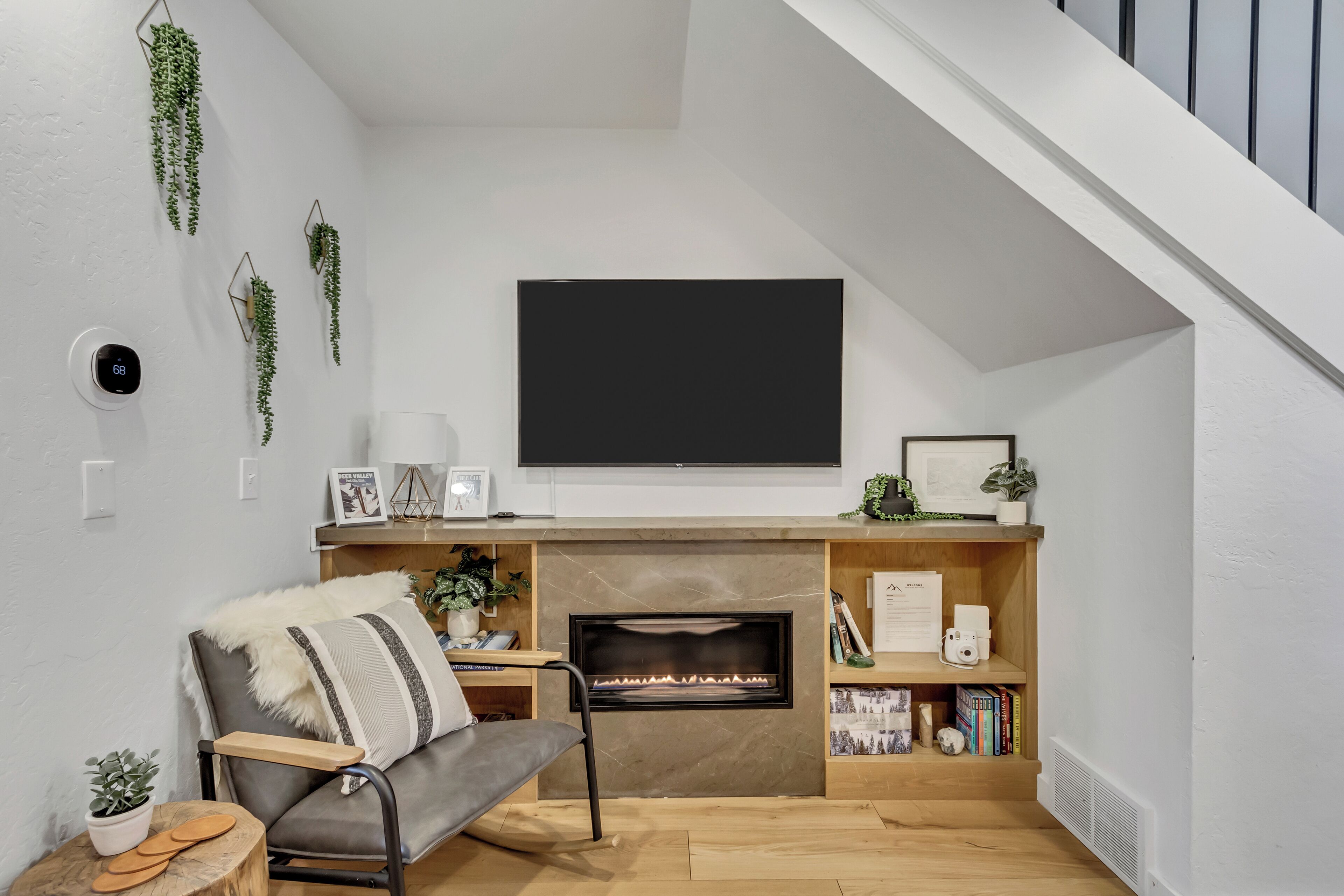 Ein modernes Wohnzimmer mit Kamin, Wandfernseher und Treppe.