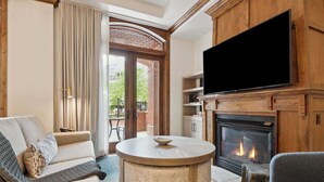 A cozy living room with a fireplace, a round coffee table, and a flat-screen TV mounted above the fireplace. - The Aspen 08ABC - 3 Bedroom Residence (Aspen)