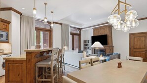 A spacious living area with a large wooden dining table, a kitchen with a built-in oven, and a fireplace. - The Aspen 08ABC - 3 Bedroom Residence (Aspen)