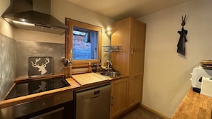 A compact kitchen with a stove, dishwasher, sink, and wooden cabinets. - Chalet, terrace, fireplace or stove, tv, 150m², Vars (Vars)