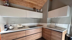 A modern kitchen with wooden cabinets, a stainless steel sink, and a kettle on the counter. - 5th floor, balcony, tv, ski locker, 65m², Vars (Vars)